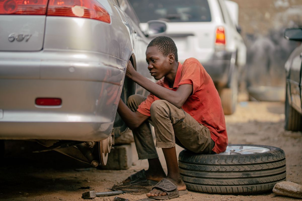 Young mechanic repairing a car tyre outdoors