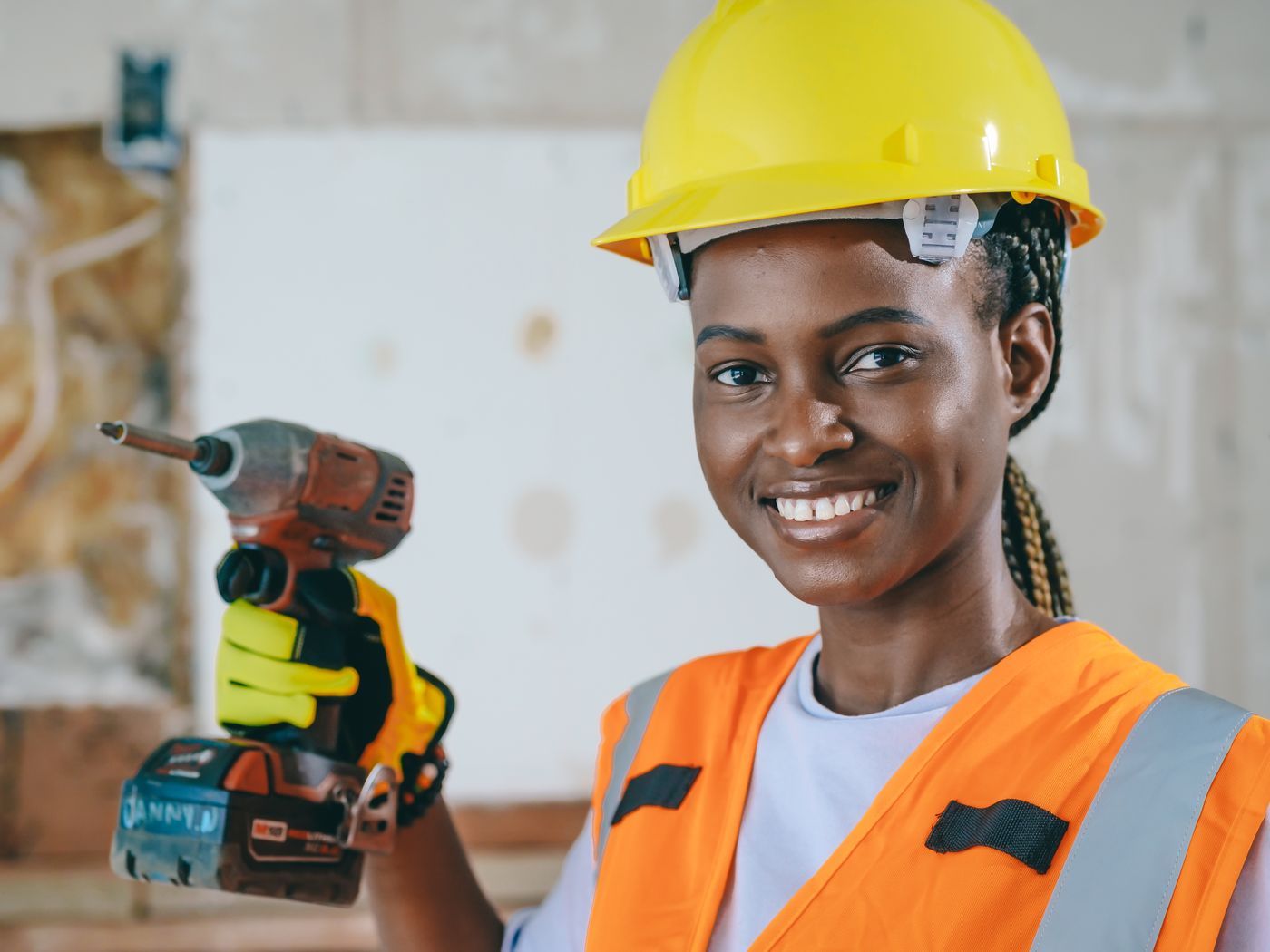 Tradeswoman in a hard hat holding a drill